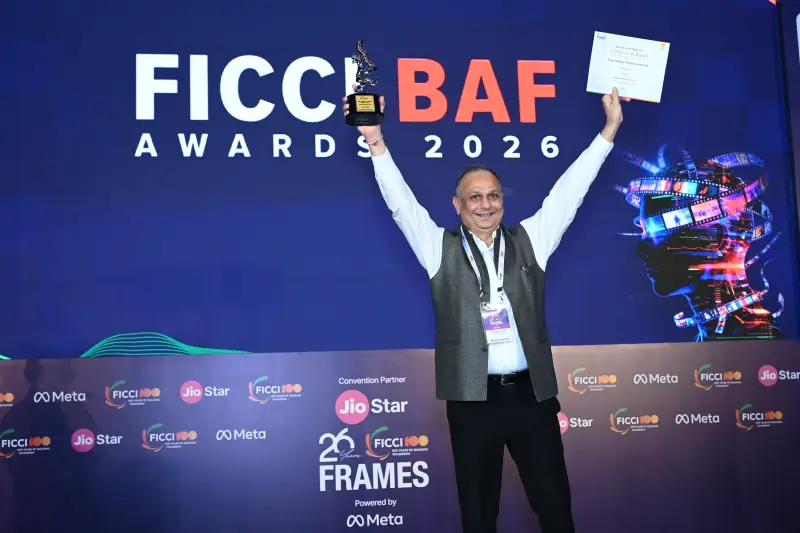 A winner lifts his trophy and certificate overhead in celebration at the FICCI BAF Awards 2026.