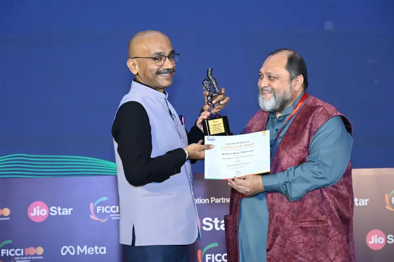A winner accepts his trophy and certificate with a handshake at the FICCI BAF Awards 2026.