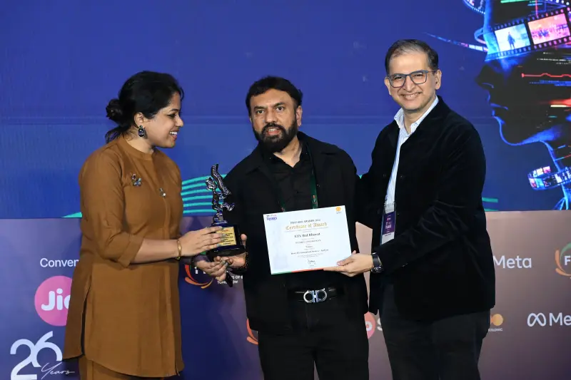 A woman presenter and a colleague hand a winner his trophy and certificate at the FICCI BAF Awards 2026.