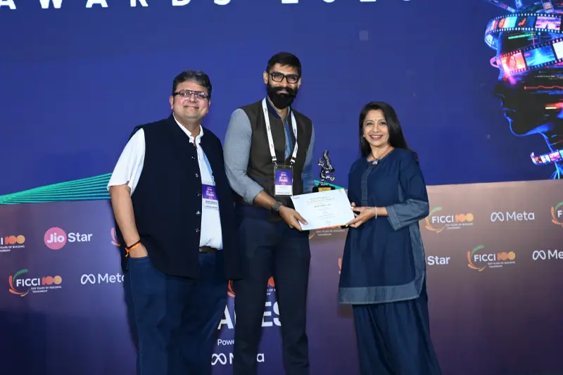 A young winner receives his trophy and certificate on the FICCI BAF Awards 2026 stage.