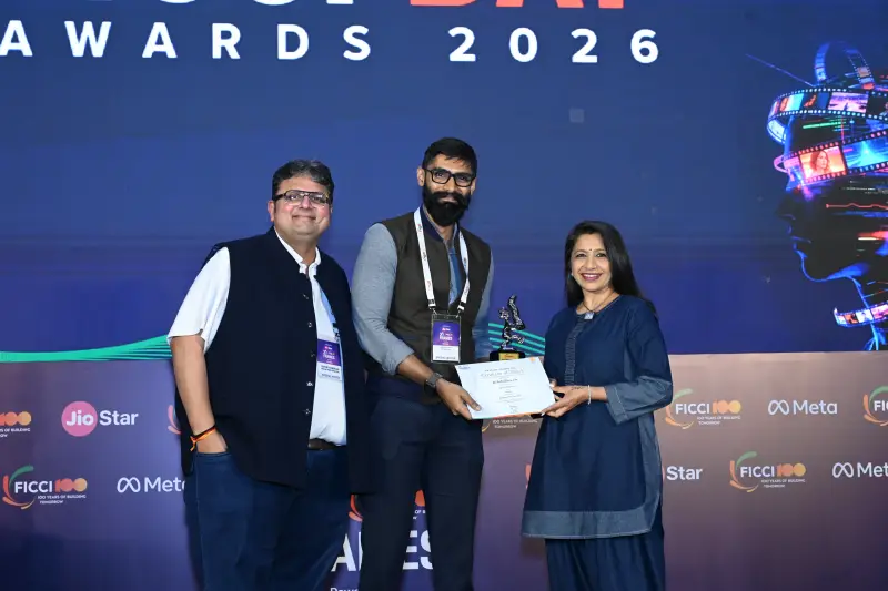 A winner is presented a trophy and certificate by two hosts at the FICCI BAF Awards 2026.