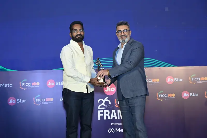 A winner accepts his trophy with a handshake at the FICCI BAF Awards 2026.