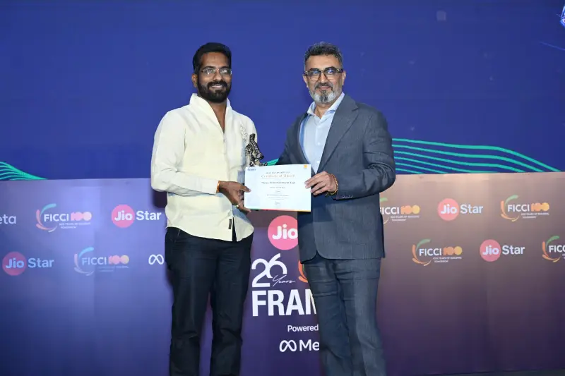 A winner holds his trophy and certificate beside the presenter at the FICCI BAF Awards 2026.