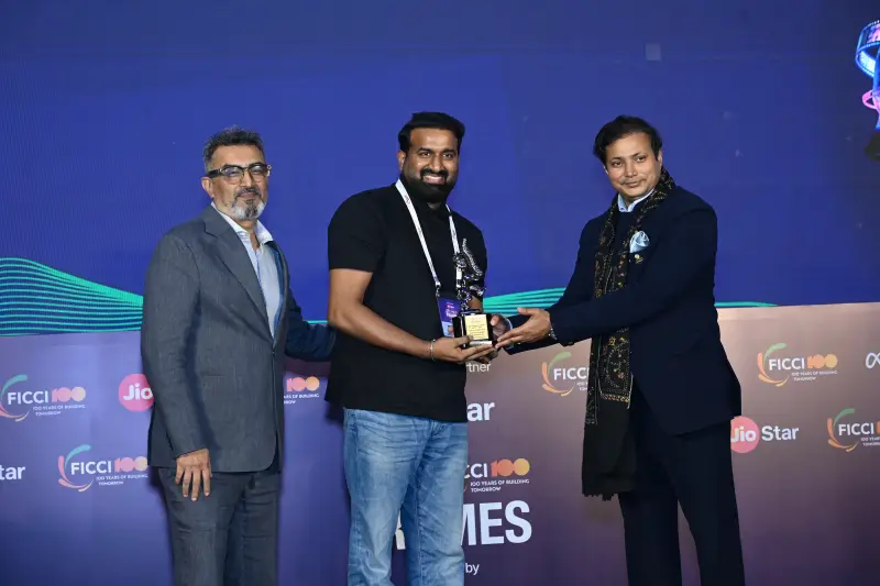 A winner is handed his award and certificate by two presenters at the FICCI BAF Awards 2026.