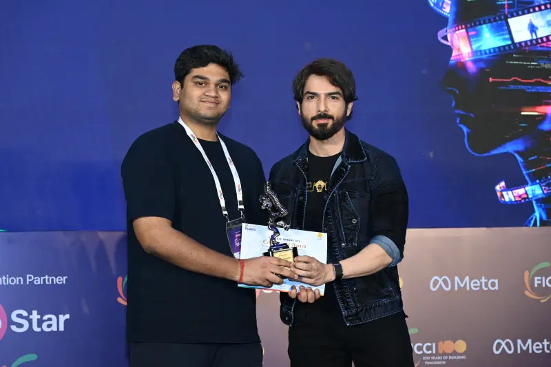 A young winner holds his trophy and certificate beside the host at the FICCI BAF Awards 2026.