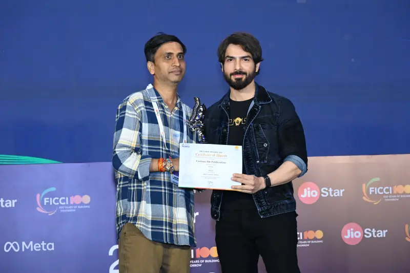 A winner in a plaid shirt holds his certificate and trophy beside the host at the FICCI BAF Awards 2026.