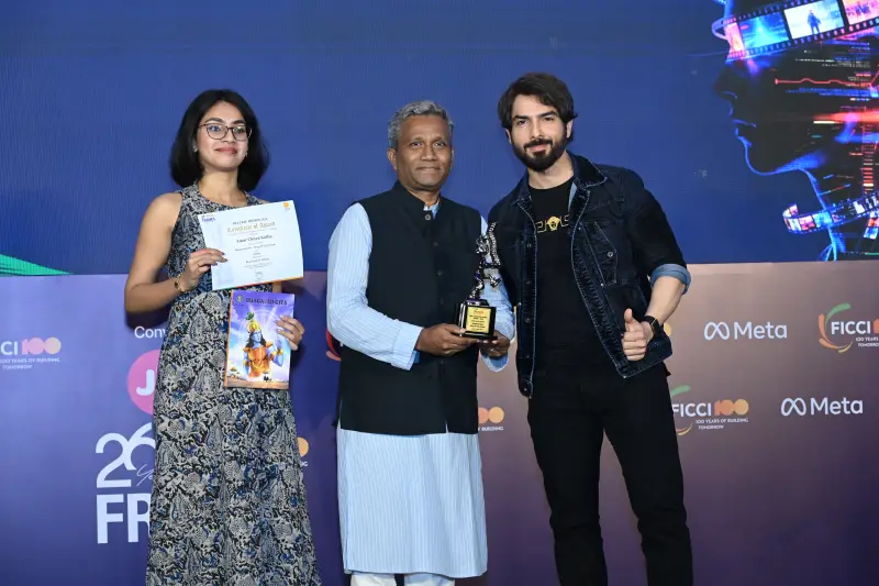 A winner receives her certificate and trophy with a presenter and the host at the FICCI BAF Awards 2026.