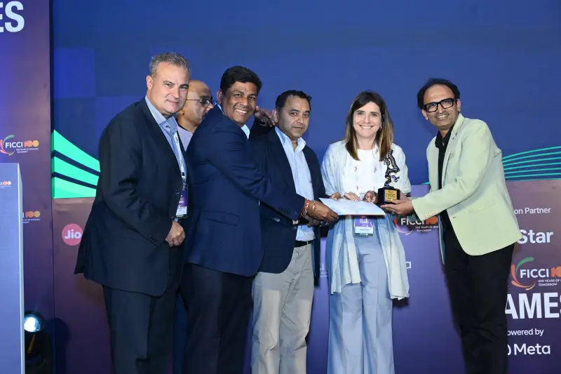 A winner receives a trophy amid a group of presenters at the FICCI BAF Awards 2026.