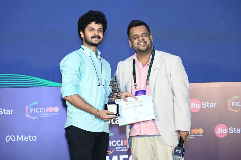 A winner holds his trophy and certificate beside the presenter at the FICCI BAF Awards 2026.